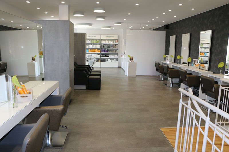 Innenraum eines Friseursalons mit Styling-Stationen, Spiegeln und Produktdisplays.