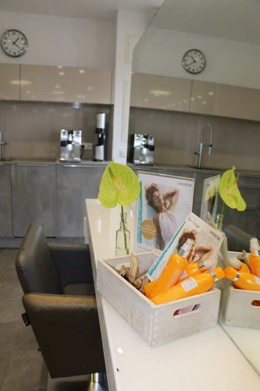 Friseursalon-Interieur mit Produktdisplay, Stuhl, Theke und zwei Uhren.