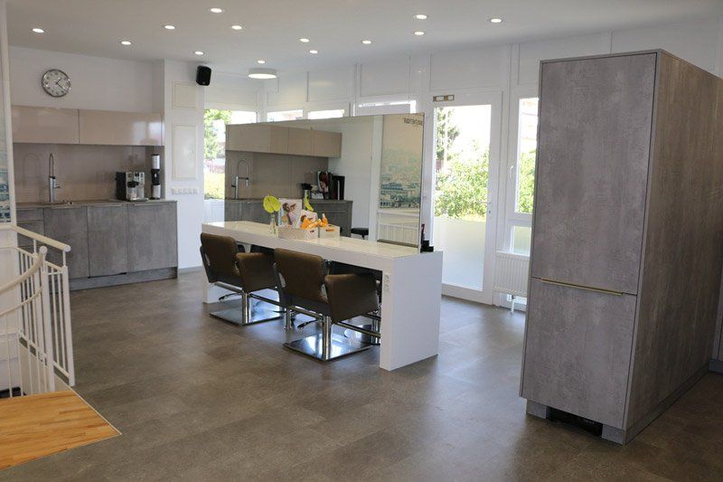 Modernes Friseursalon-Interieur mit Sitzgelegenheiten, Küche und großen grauen Lagerschränken.