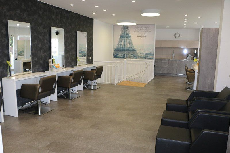 Inneneinrichtung eines Friseursalons mit Styling-Stationen, Wartebereich und Eiffelturm-Kunstwerk.