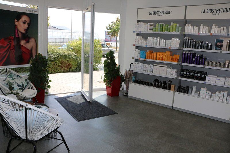 Ein Salon-Interieur mit Produktregalen, offener Tür, Wartebereich und einer Anzeige mit einer Frau in einem roten Kleid.