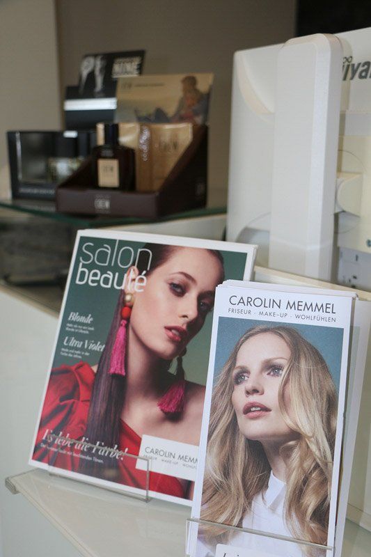 Ausstellung eines Schönheitsmagazins für den Salon; zeigt eine Frau mit rosa und violettem Haar und anderen Schönheitsprodukten.