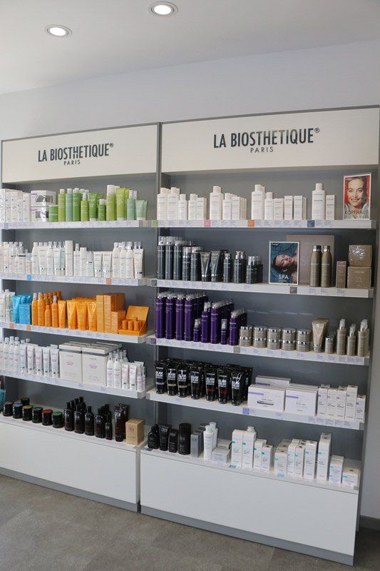 Regale mit Haar- und Hautpflegeprodukten von La Biosthetique Paris. Verschiedene Farben und Größen, in einem Einzelhandelsumfeld.