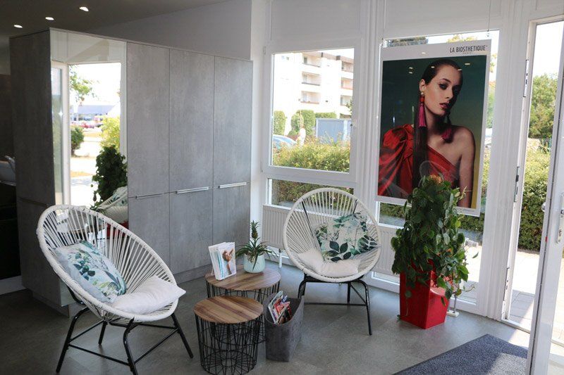 Loungebereich mit weißen Stühlen, kleinen Tischen und einem großen Poster einer Frau mit roten Haaren.