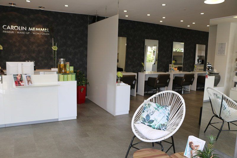 Inneneinrichtung eines Friseursalons, Dekor in Weiß und Dunkelgrau. Rezeption, Stylistenstationen und Loungesessel.