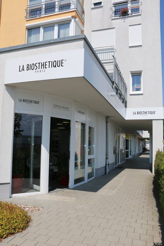 La Biosthetique Pariser Geschäft mit weißer Fassade, Glasfenstern und einem Gehweg.