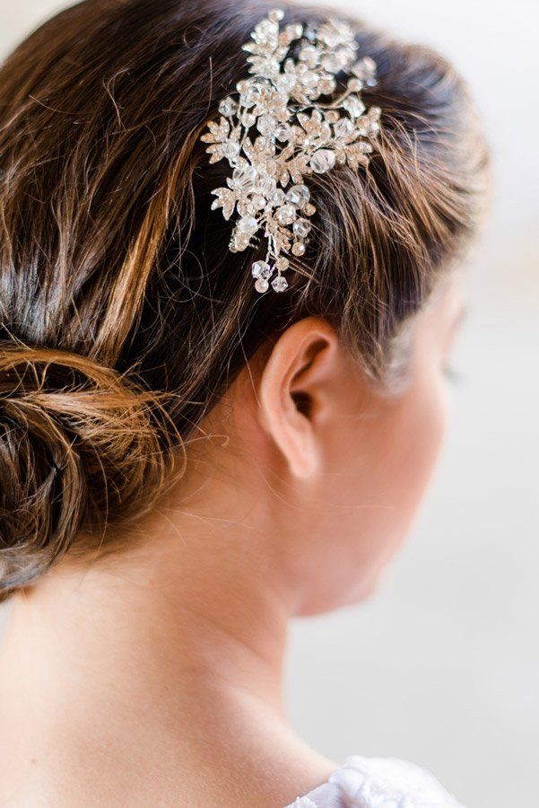 Frau mit braunem Haar in einem tiefen Dutt, geschmückt mit einem glitzernden Haarkamm.