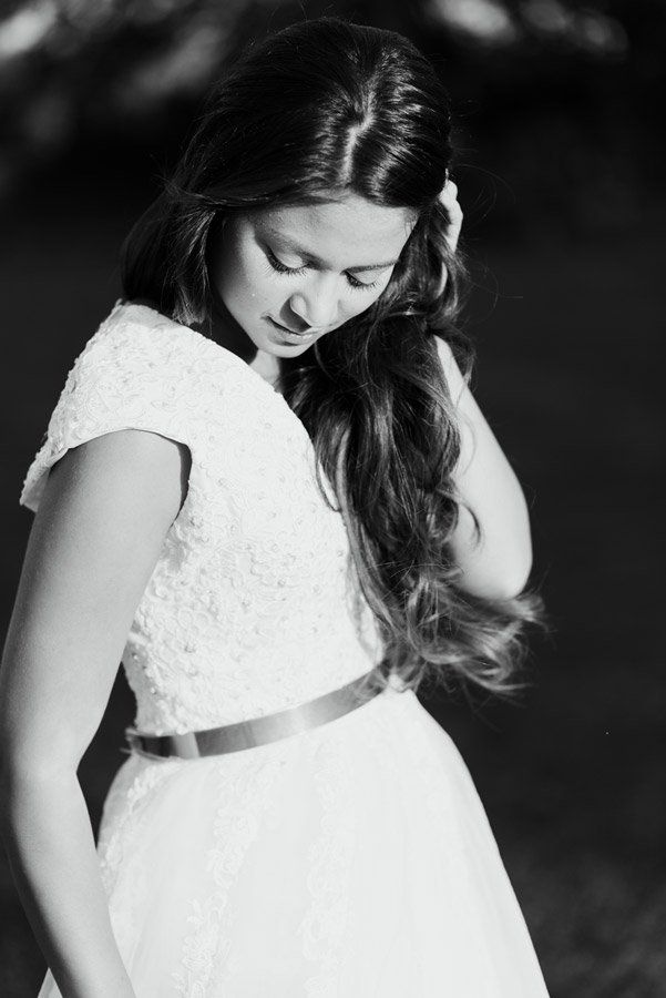 Frau im weißen Kleid, Kopf nach unten geneigt, wallendes Haar, im Freien.