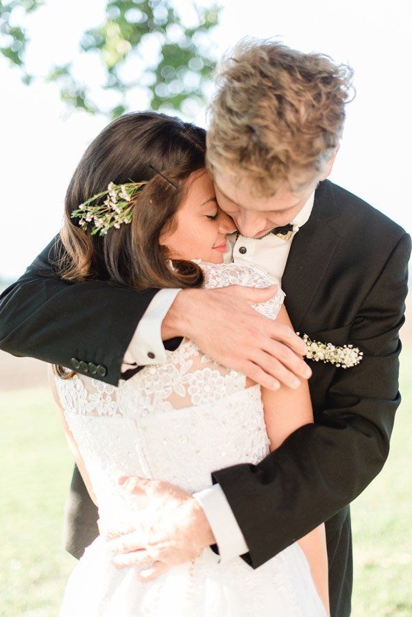 Braut und Bräutigam umarmen sich im Freien; sie trägt ein weißes Kleid, er einen Smoking.