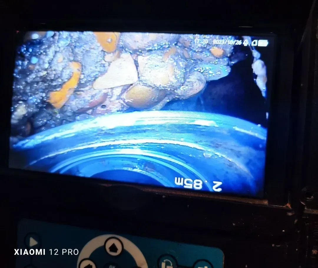 Una pantalla borrosa muestra una escena submarina azul y naranja con rocas y un tubo azul curvado.