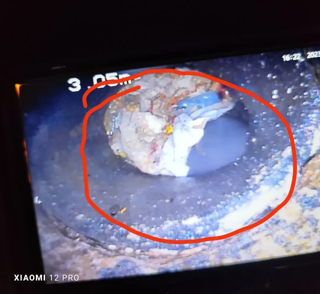 Primer plano del interior de una tubería con una obstrucción circular resaltada en rojo en la pantalla de un monitor.