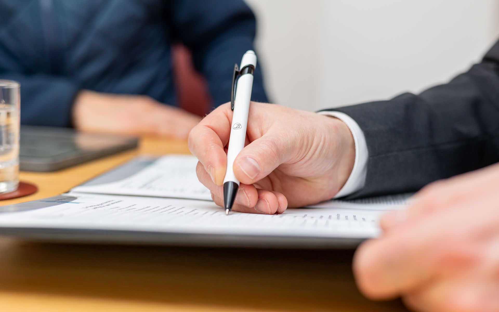 Eine Person schreibt mit einem Stift auf ein Blatt Papier.