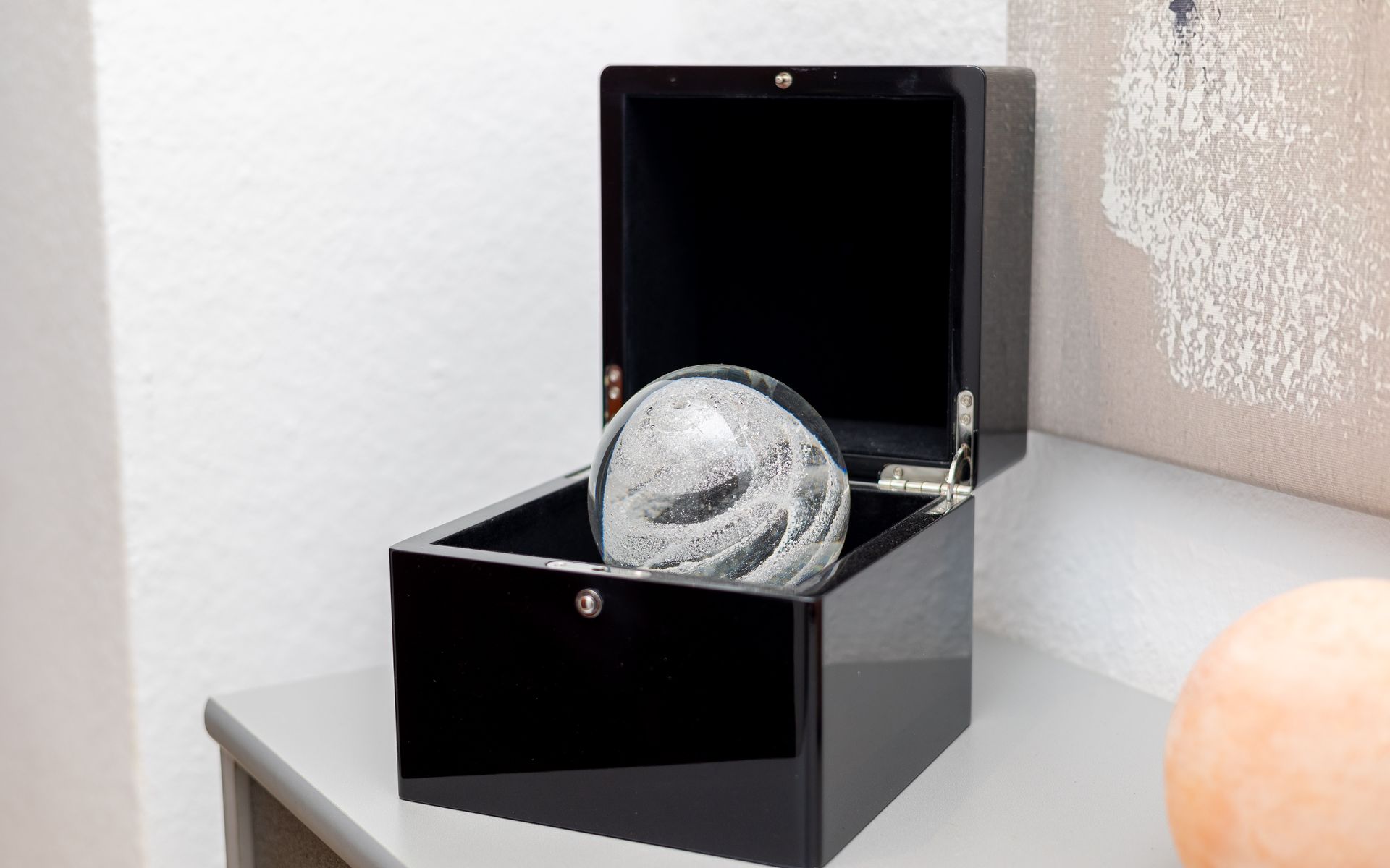 Eine Glaskugel befindet sich in einer schwarzen Box auf einem Tisch.