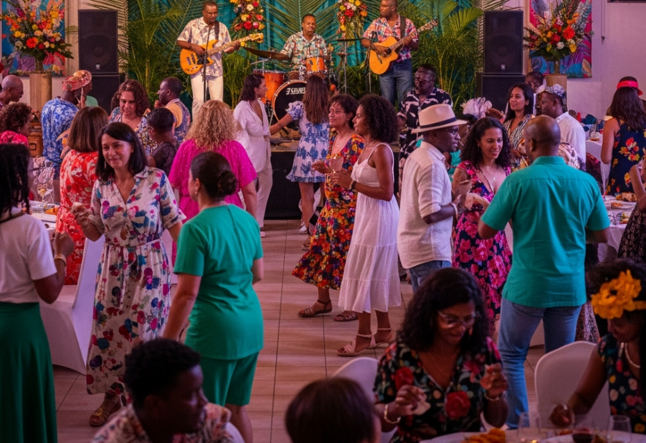 Des personnes discutent et dansent lors d'une fête en intérieur, avec un groupe de musique jouant en fond sonore.