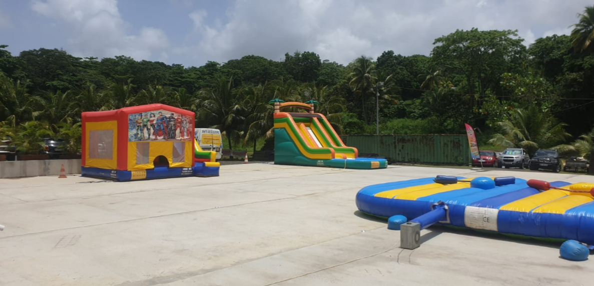 Quatre randonneurs cheminent le long d'un sentier tropical luxuriant à flanc de falaise, surplombant l'océan et une île conique au loin.