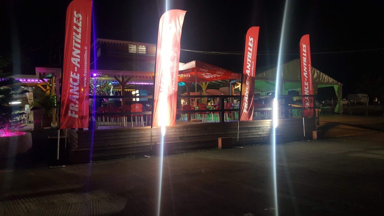 Une terrasse en bois ornée, illuminée la nuit par des lumières vives.