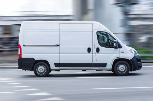 Camionnette de livraison blanche avec un flou de mouvement en arrière-plan.