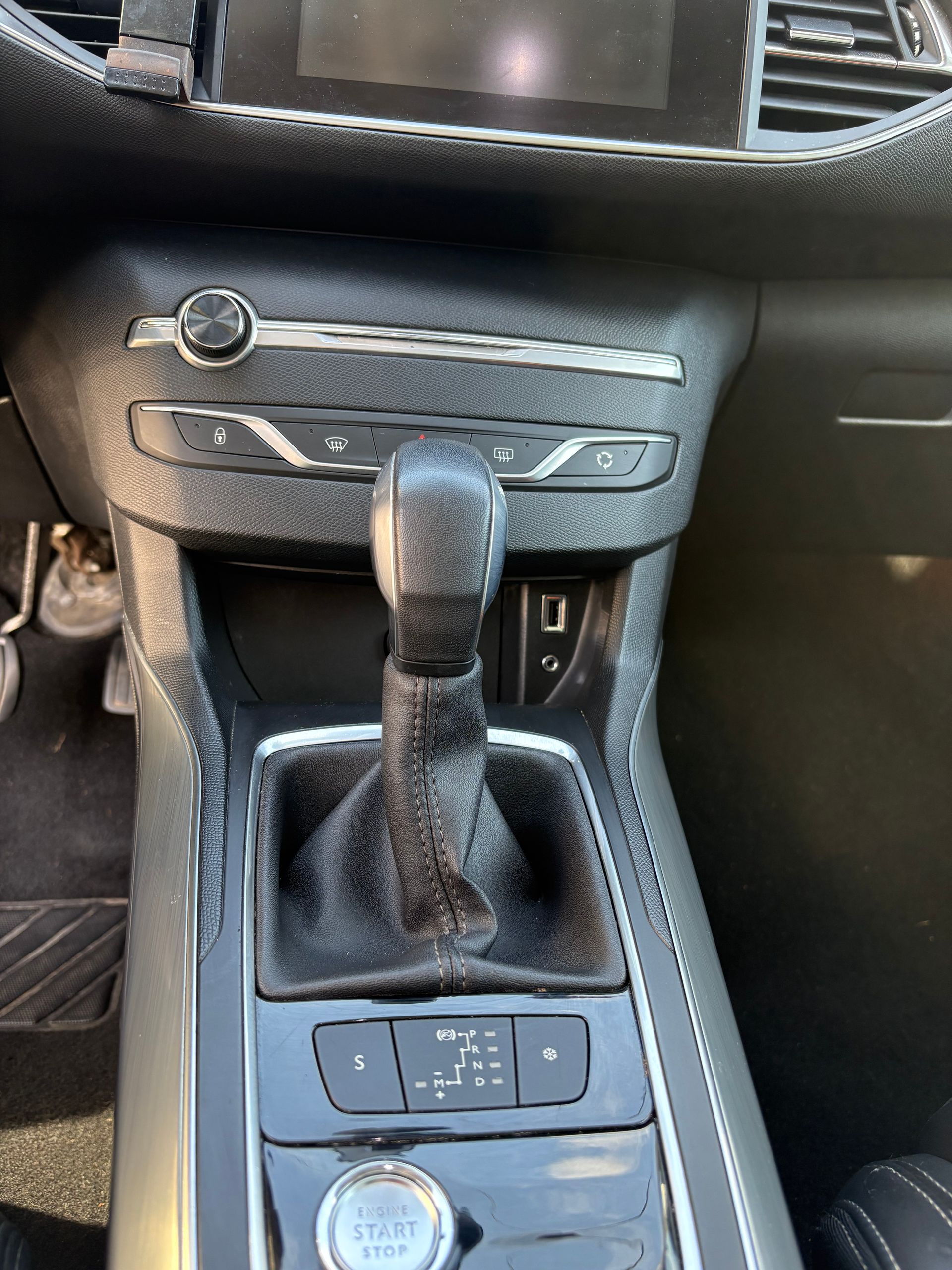 Console centrale de voiture avec levier de vitesse, boutons de commande et tableau de bord.