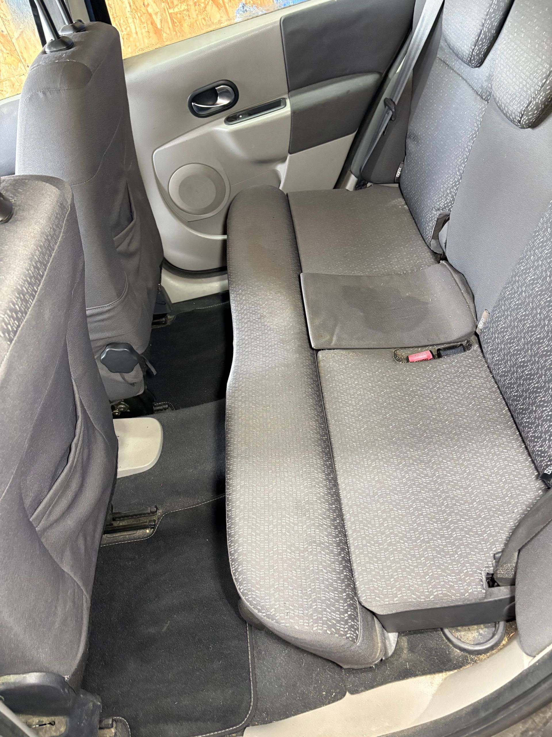 Banquette arrière d'une voiture en tissu, avec sièges rabattables et ceintures.