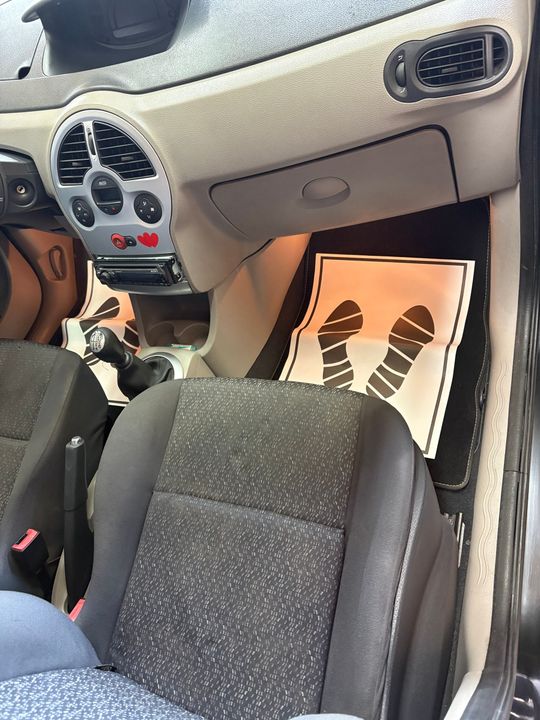 Intérieur de voiture avec les jambes d'une personne sur le siège conducteur et des tapis de sol appuyés contre le plancher côté passager.