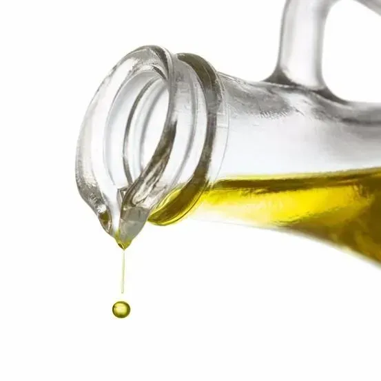 Se vierte una botella de aceite de oliva en un recipiente de vidrio.