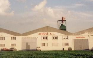 Un gran edificio blanco con techo verde está situado en medio de un campo.