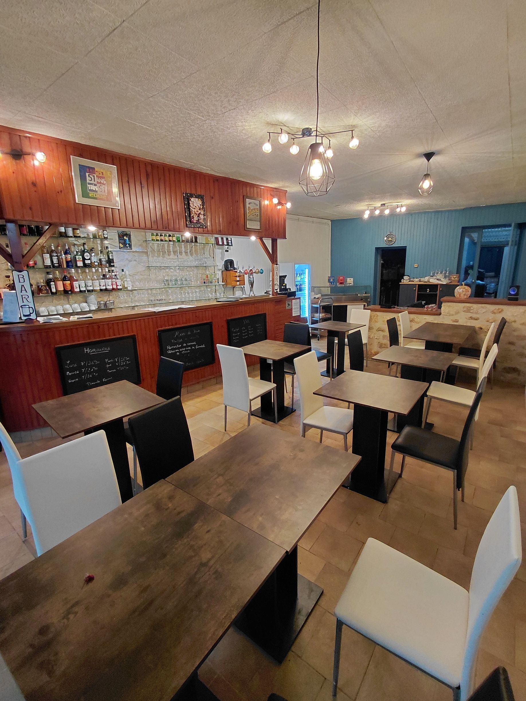 Intérieur d'un restaurant avec tables, chaises, bar et luminaires.