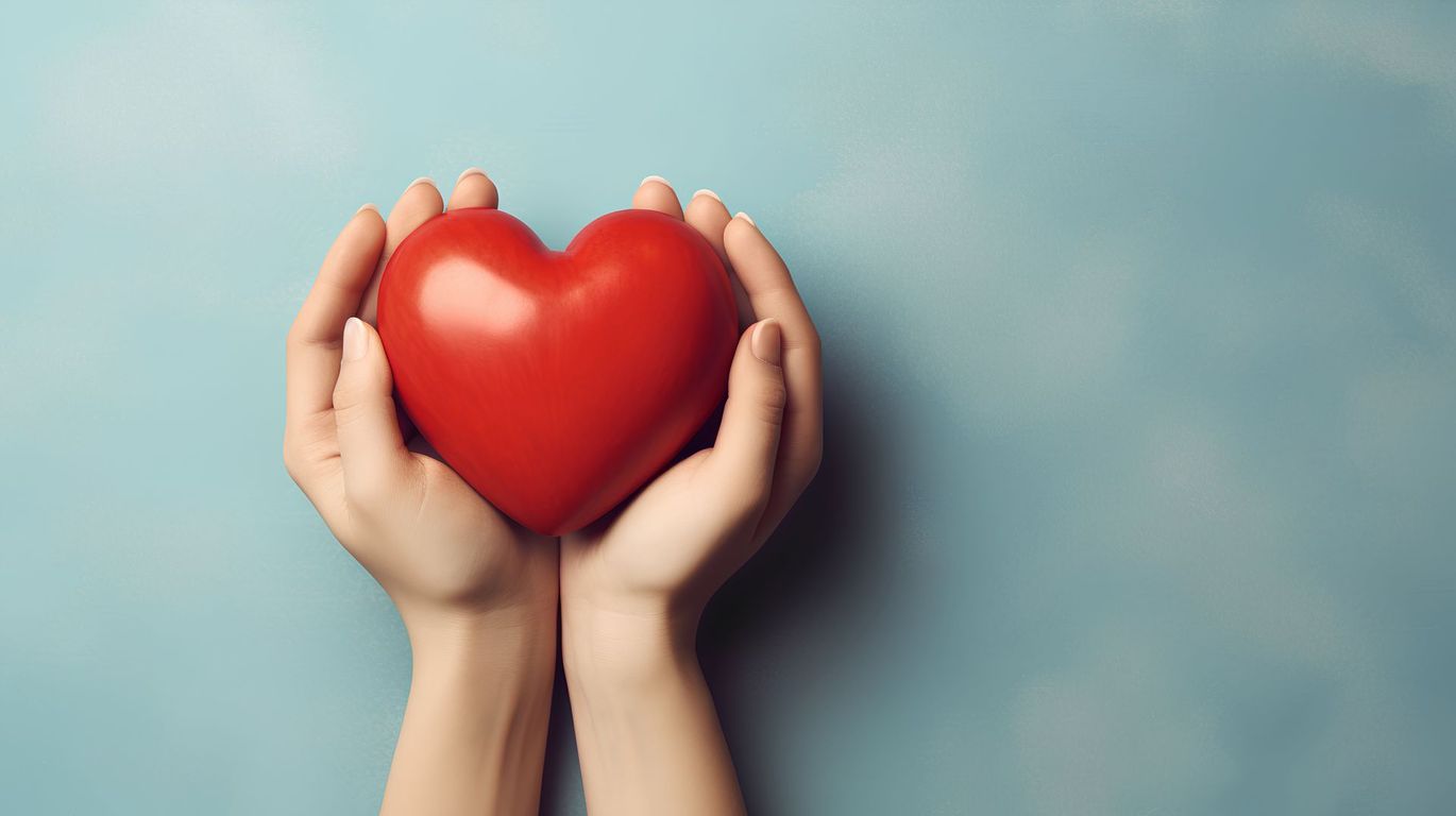 Hände halten ein rotes Herz auf hellblauem Hintergrund.