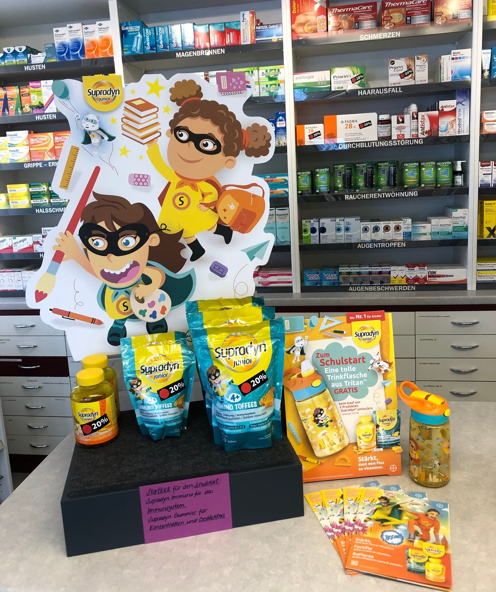Ausstellung von Vitaminen und Snacks für Kinder mit Zeichentrickfiguren in einer Apotheke.