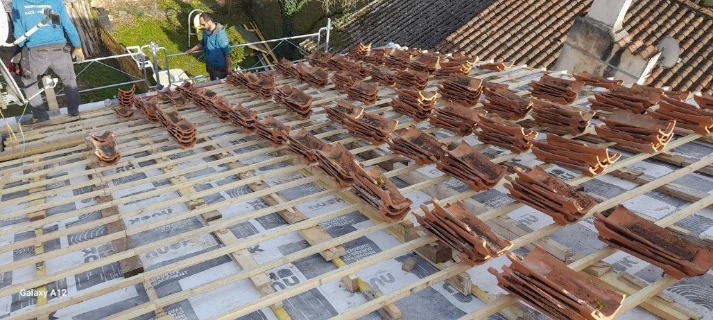 Couvreurs posant des tuiles en terre cuite sur un toit partiellement construit.