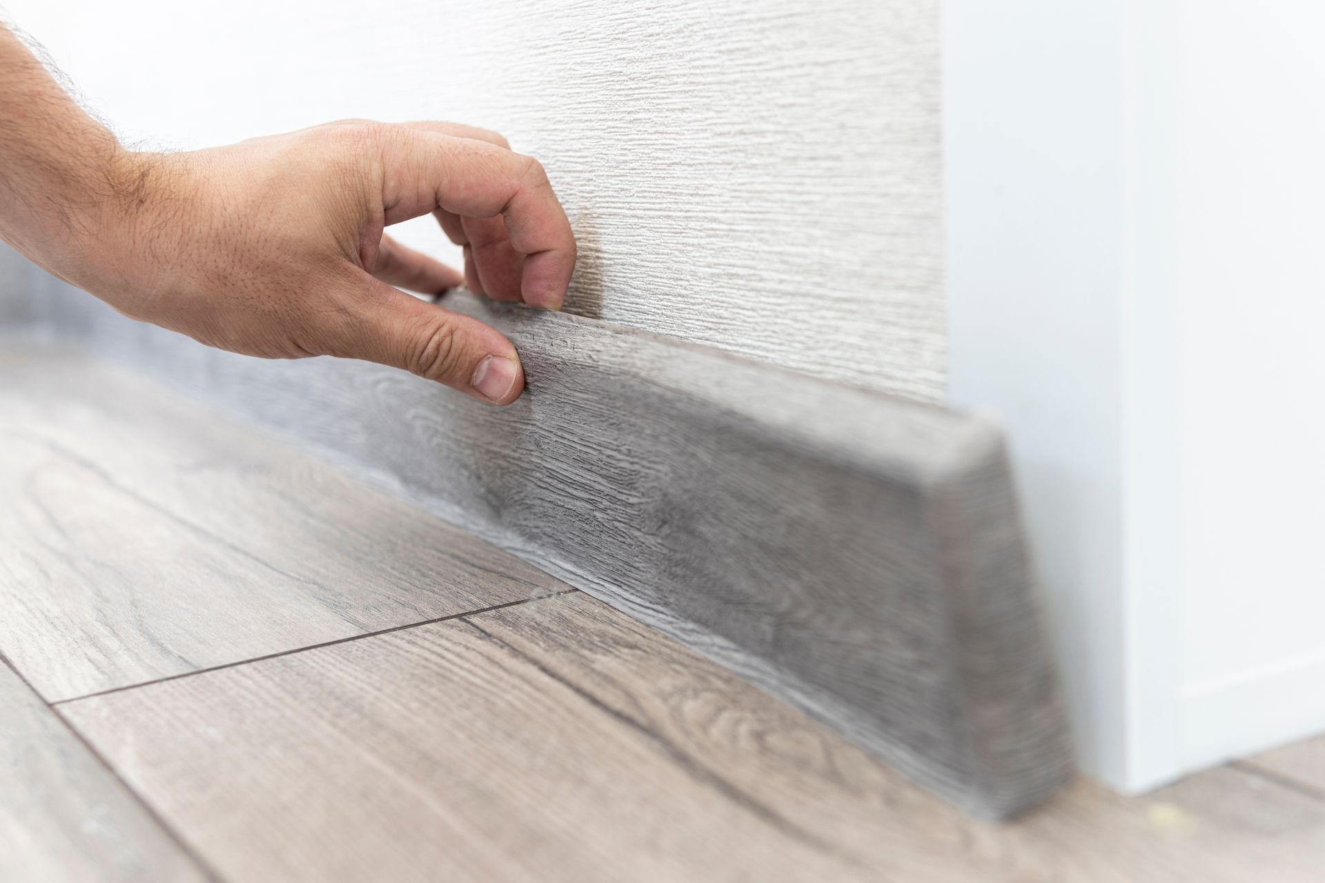 Une personne posant des plinthes en bois.