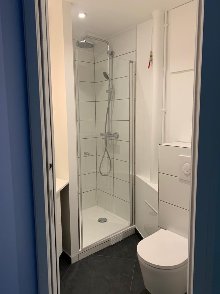 Petite salle de bains blanche avec douche et toilettes