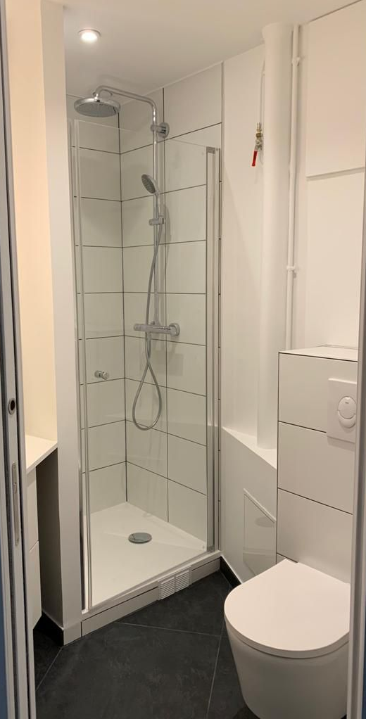 Petite salle de bains blanche avec douche et toilettes