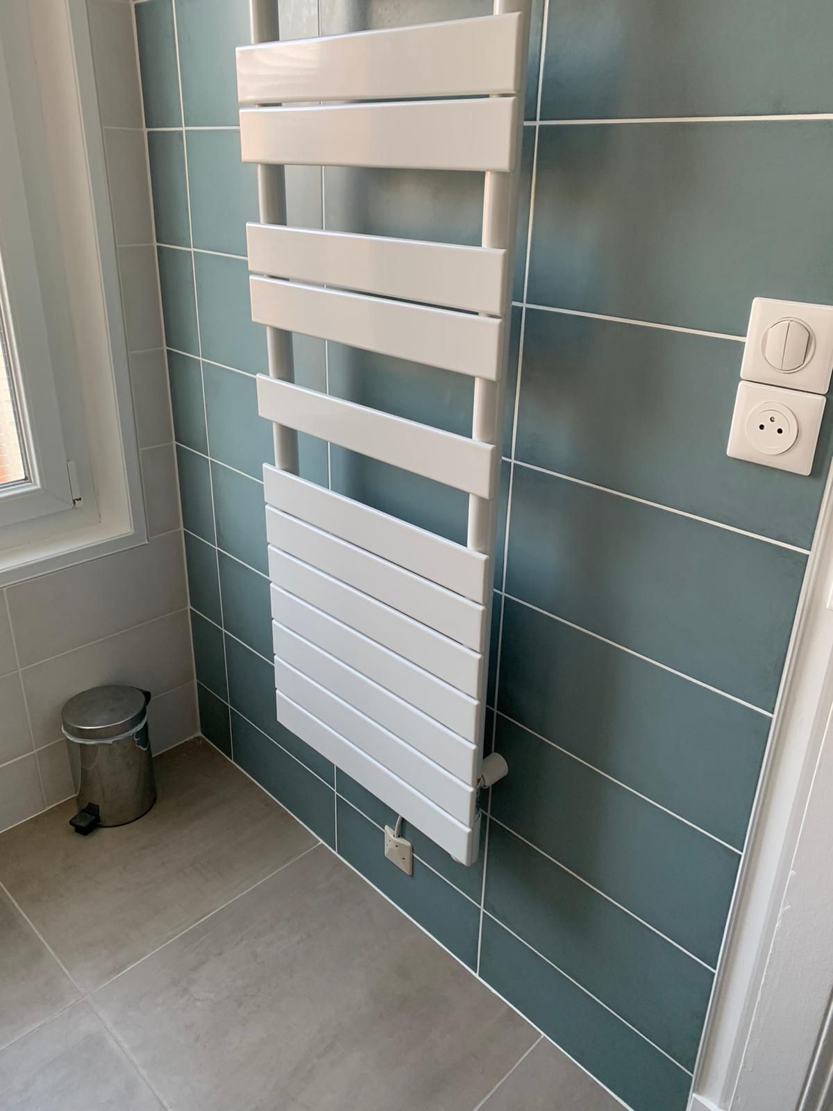 Sèche-serviettes blanc sur un mur carrelé