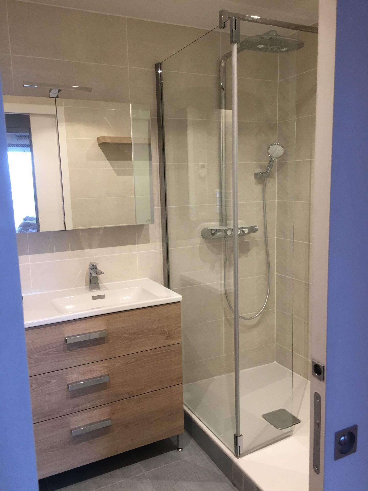 Petite salle de bains avec douche, meuble-lavabo et miroir