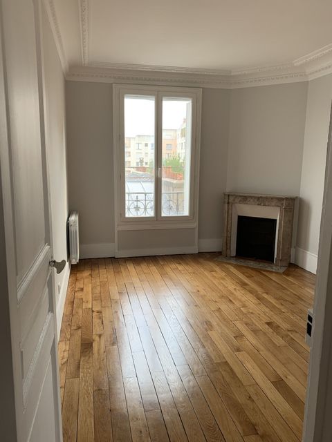 Pièce vide avec parquet, fenêtre et cheminée