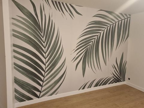 Mur recouvert de papier peint à grands motifs de feuilles de palmier vertes