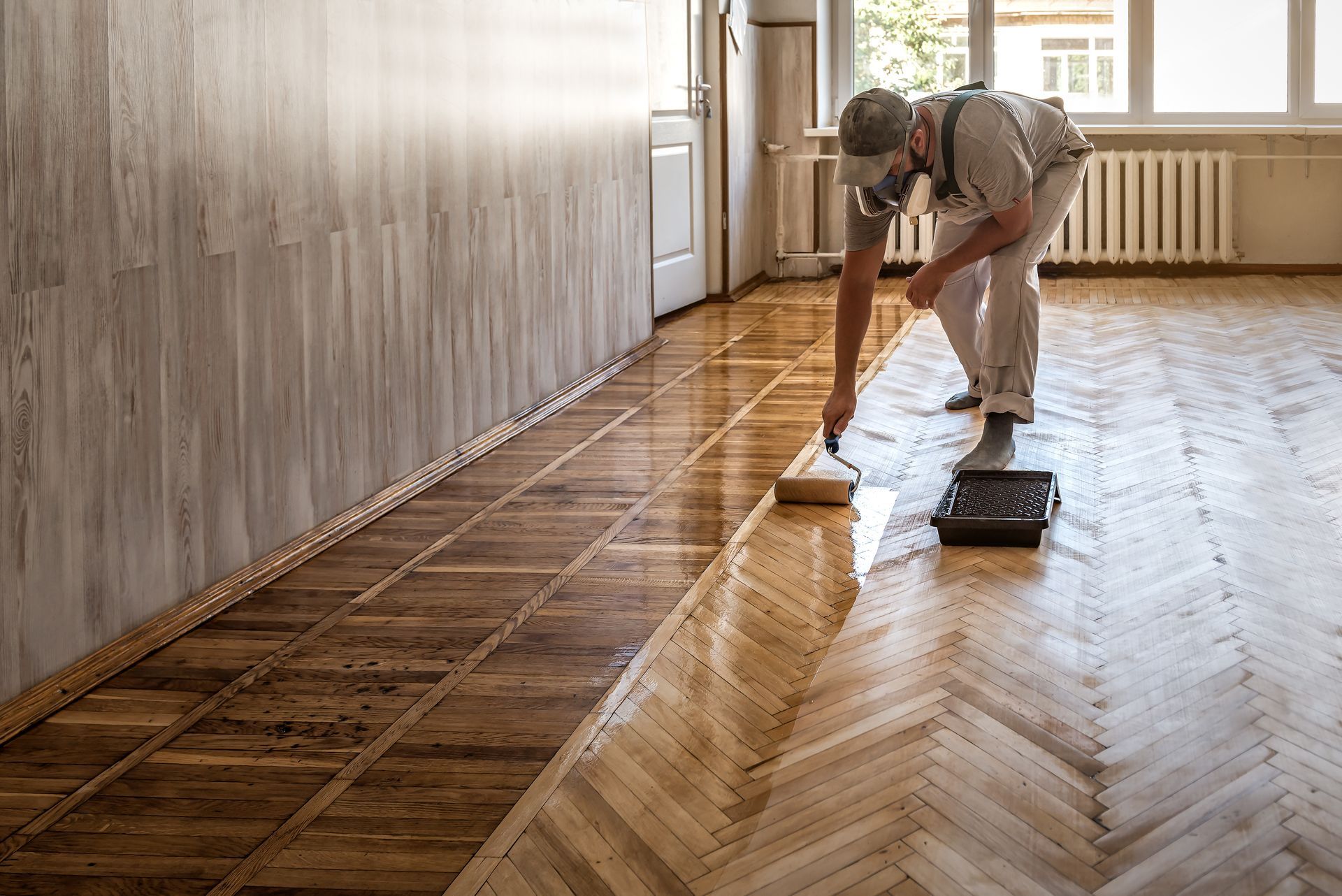 Une personne applique du vernis sur un parquet