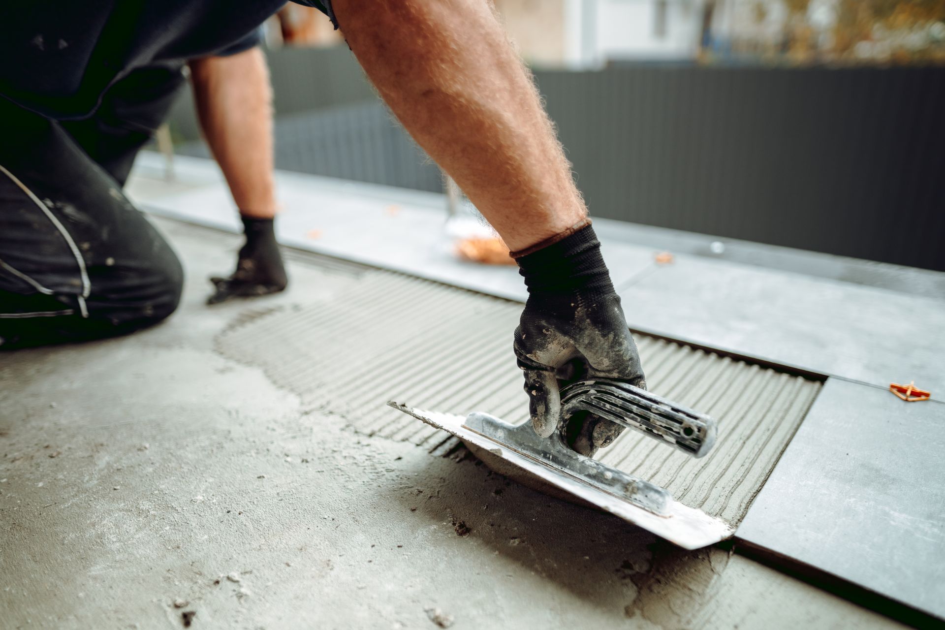 Un homme pose des carreaux sur une surface en béton