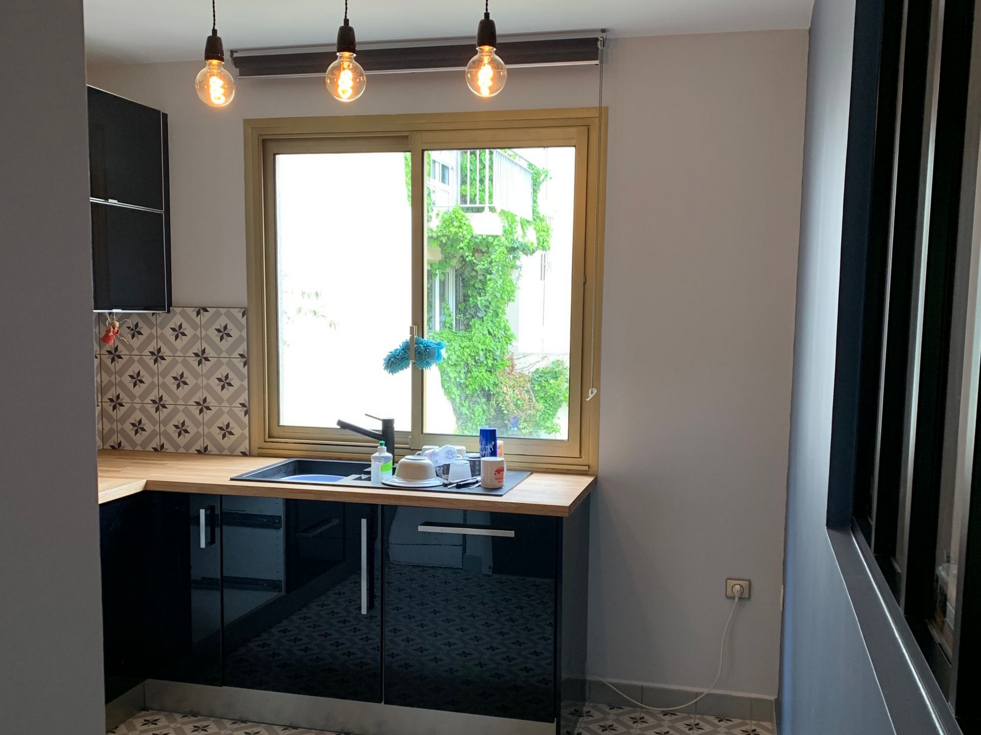 Cuisine avec des placards noirs et un plan de travail en bois