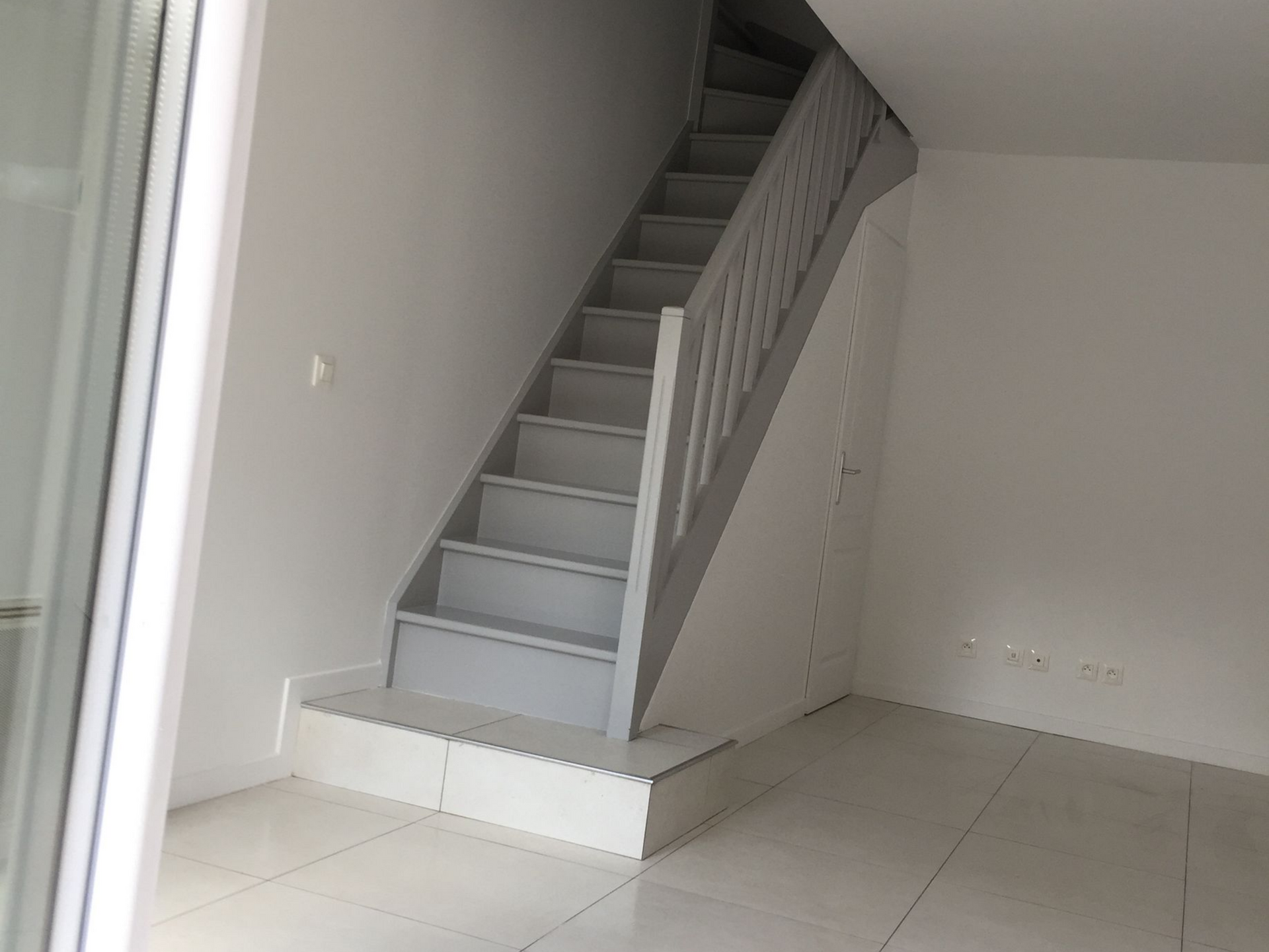 Escalier en bois dans une pièce au sol carrelé