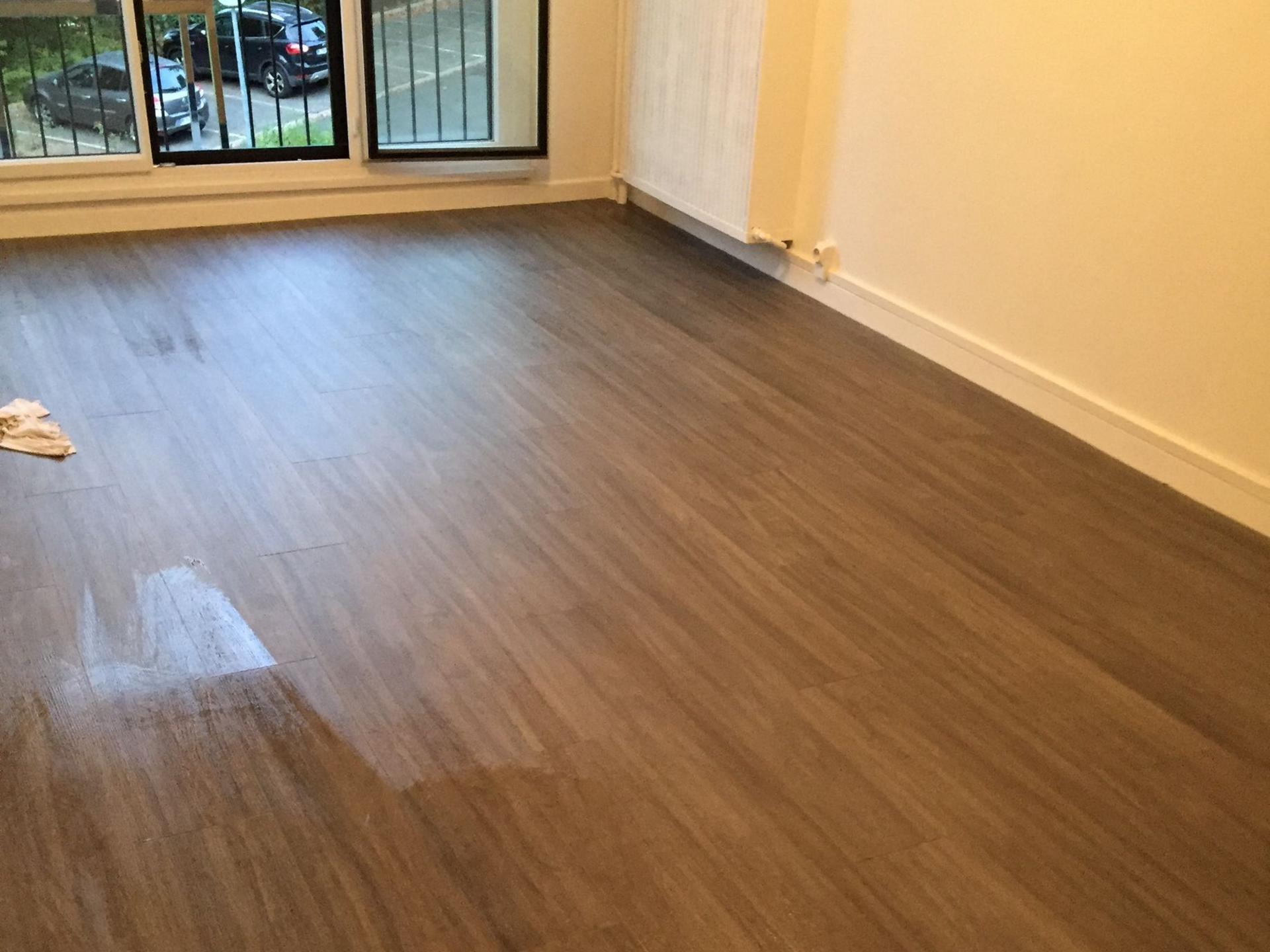 Chambre avec parquet, deux fenêtres et murs blancs