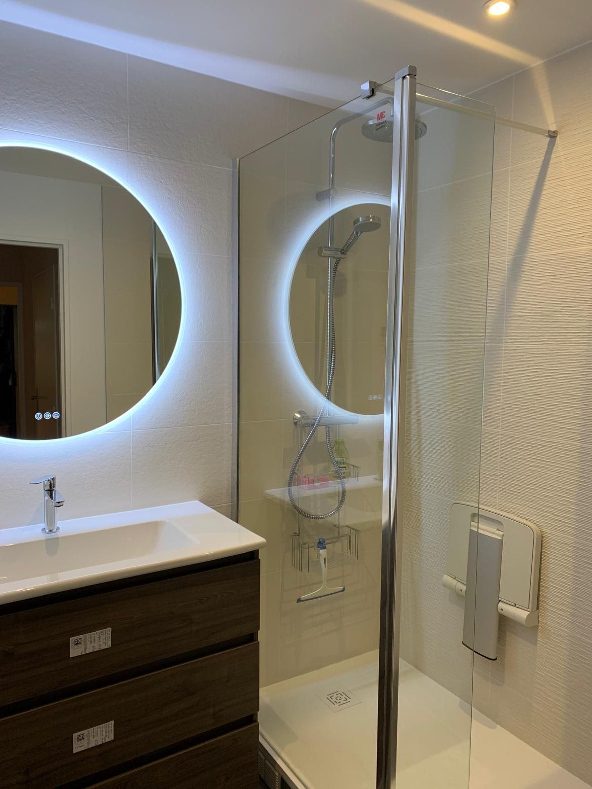 Une salle de bains moderne avec un meuble-lavabo suspendu et un miroir circulaire rétroéclairé