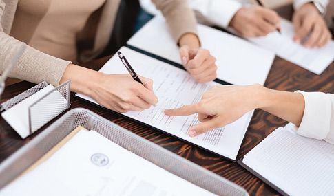 Un grupo de personas está sentada en una mesa firmando papeles.