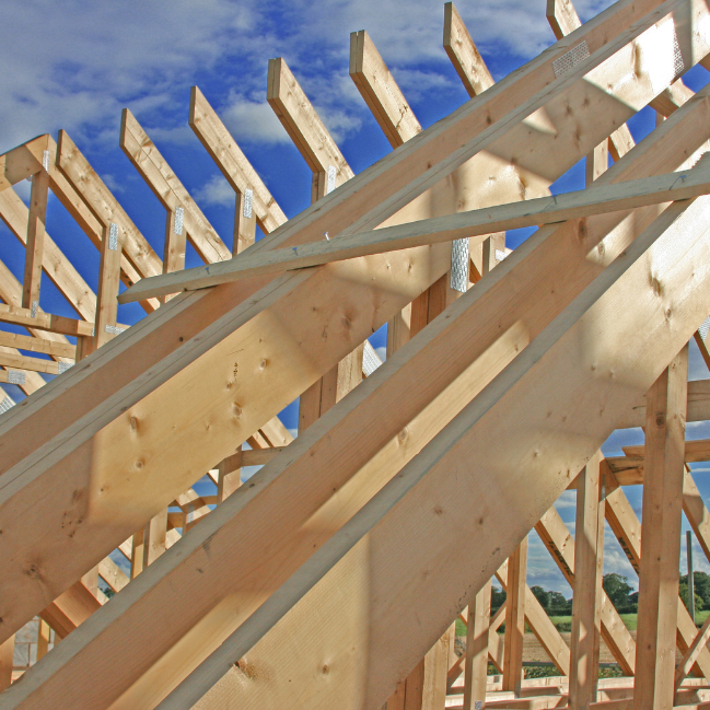 Charpente de toit en bois contre un ciel bleu.