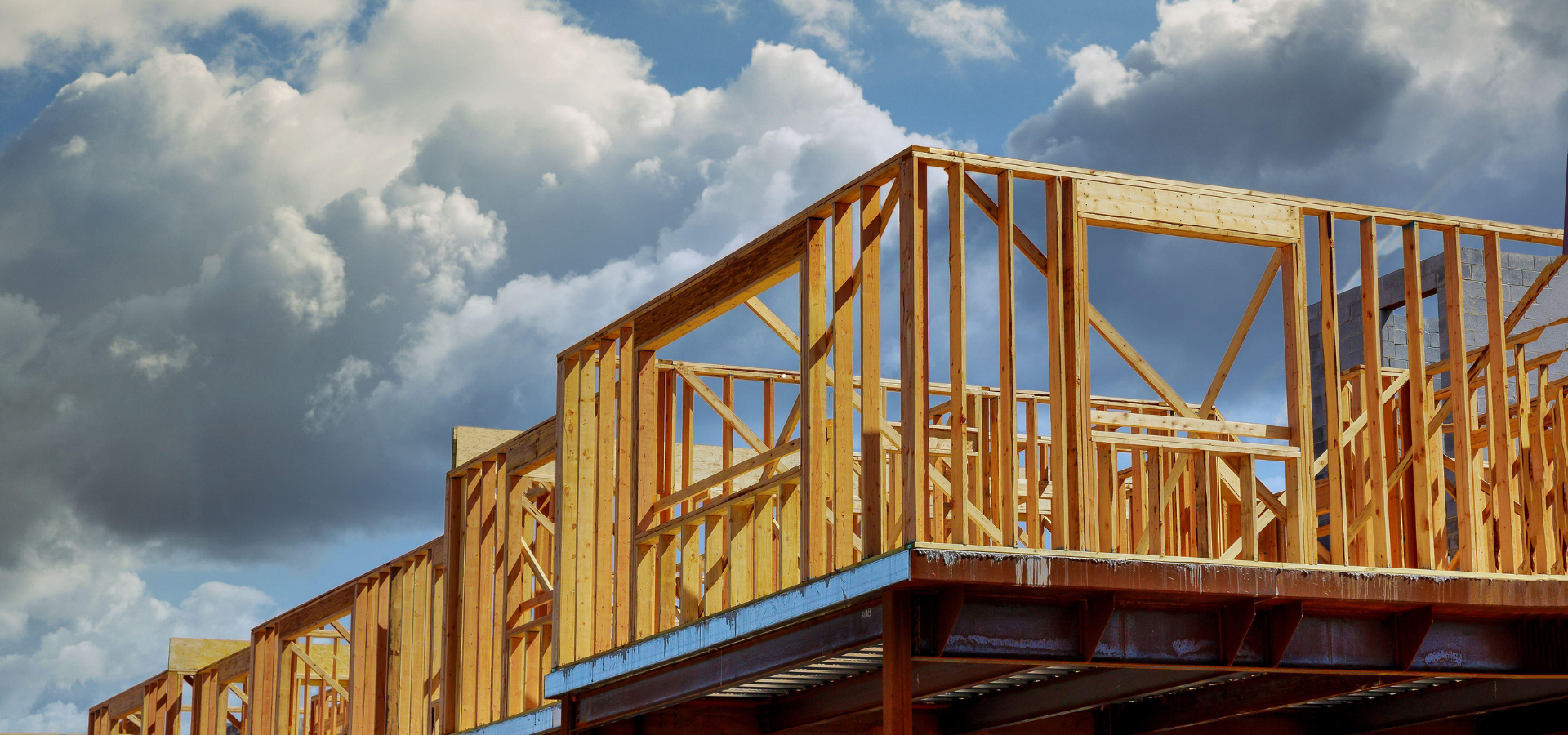 Ossature en bois d'un bâtiment en construction, sur fond de ciel nuageux.
