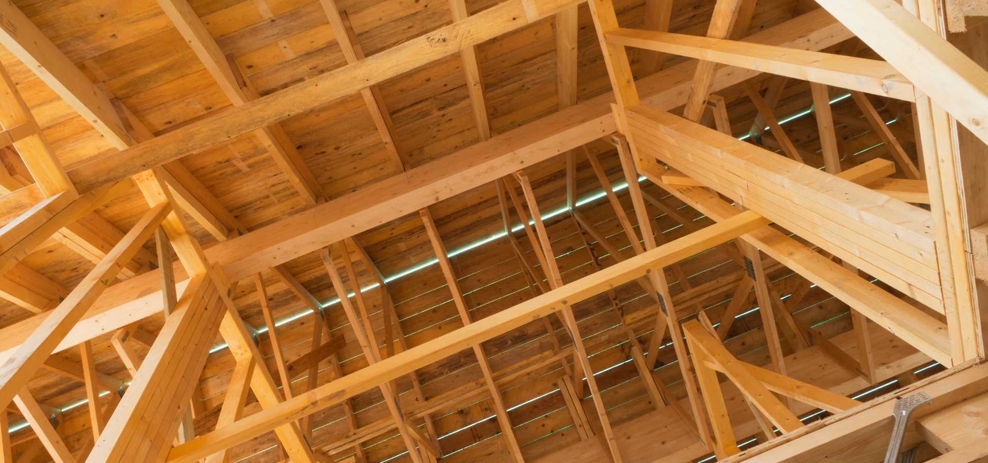 Chevrons et poutres en bois d'une structure de toit sous différents angles, avec des tons de bois clair.