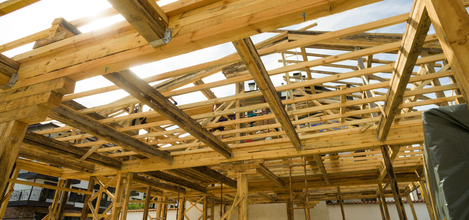 Charpente en bois d'un bâtiment en construction, poutres formant la toiture et les murs, lumière naturelle.