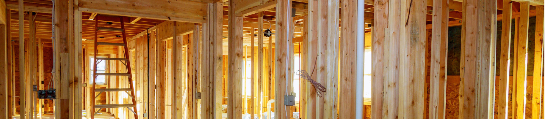 Ossature en bois d'un bâtiment en construction, avec montants verticaux et supports horizontaux.