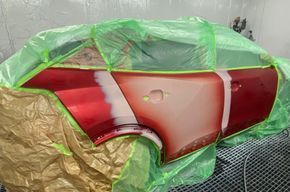 Die rot-weiße Heckklappe des Autos wurde zum Lackieren mit grüner Folie abgeklebt.